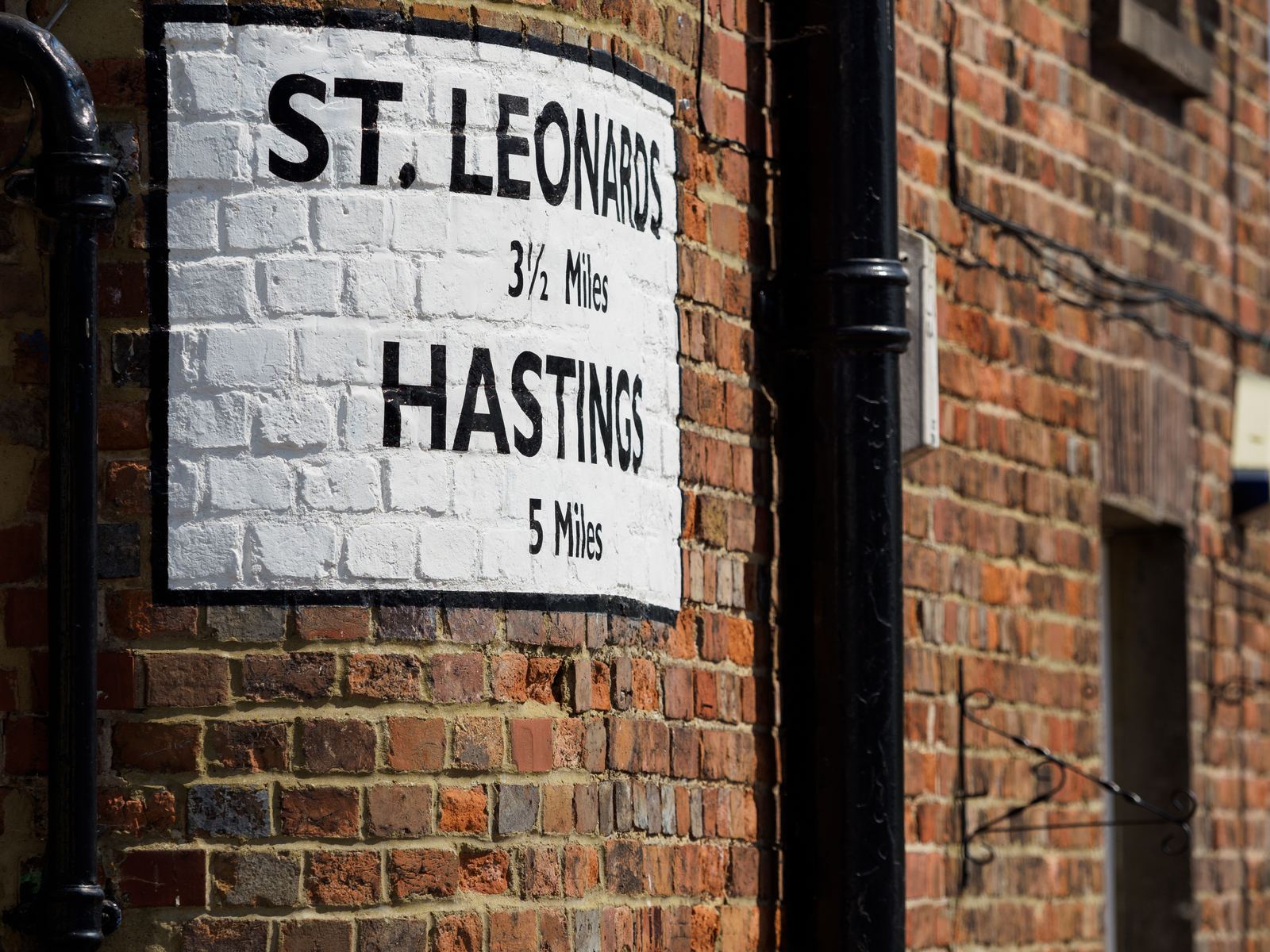 The painted St Leonards and Hastings mileage sign on a brick wall